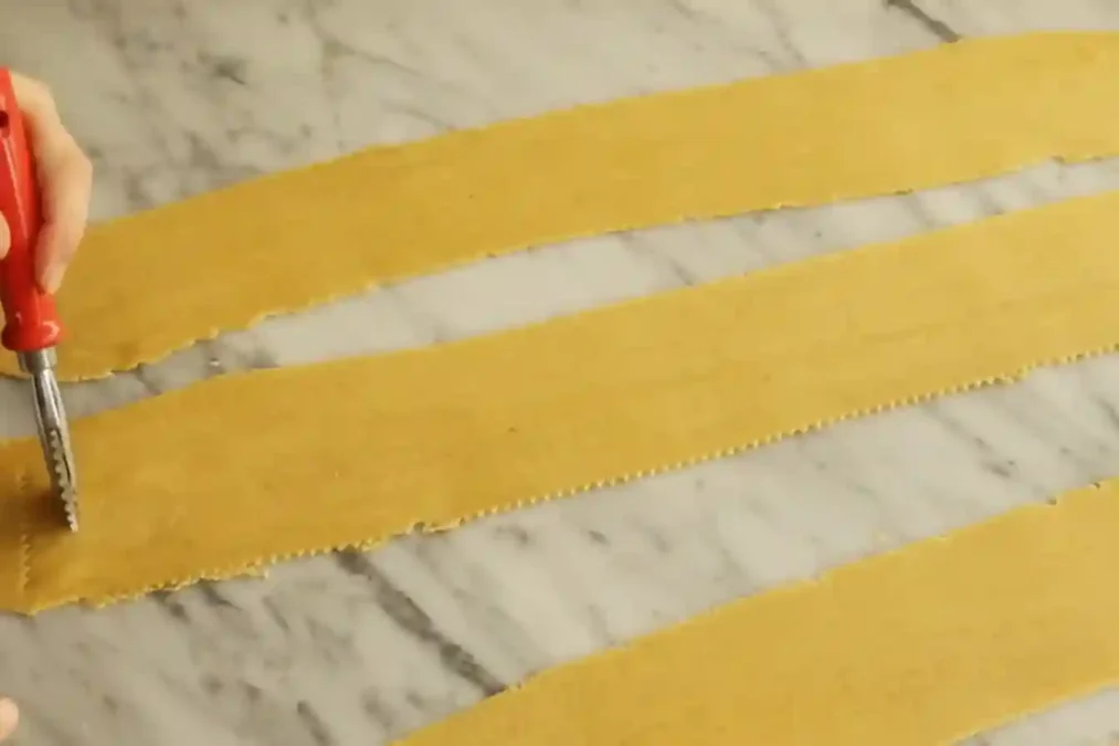 Découpe de bandes de pâte à chebakia avec une roulette dentelée