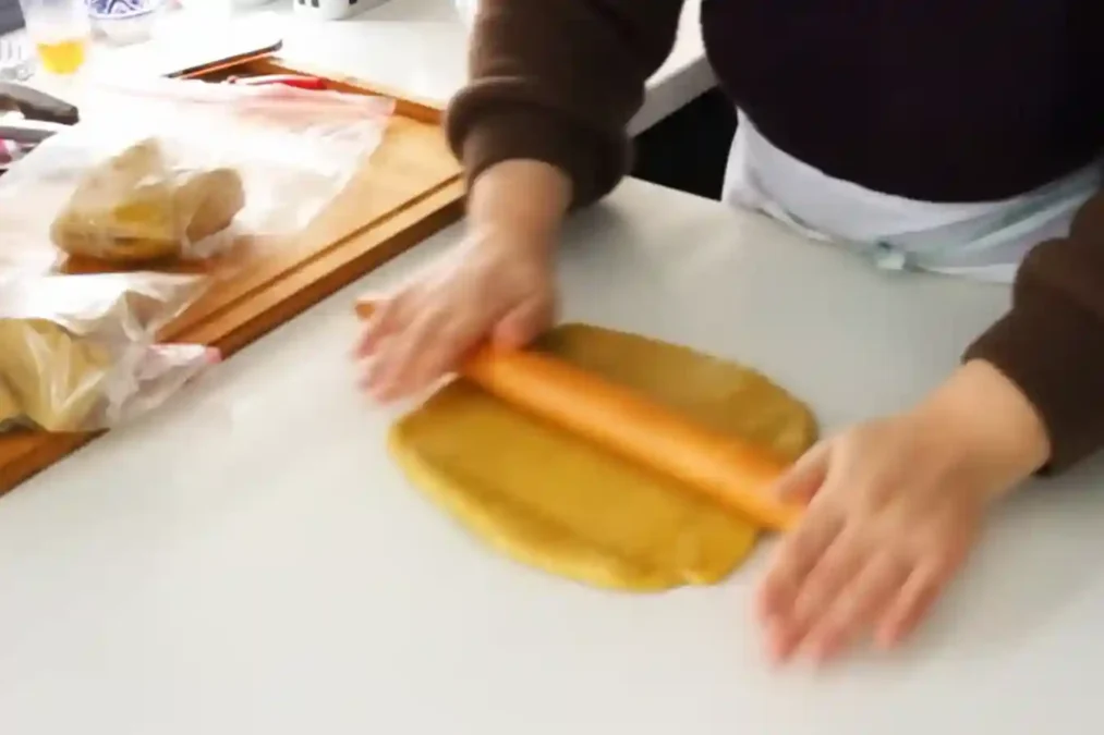 Étaler la pâte à chebakia avec un rouleau sur un plan de travail