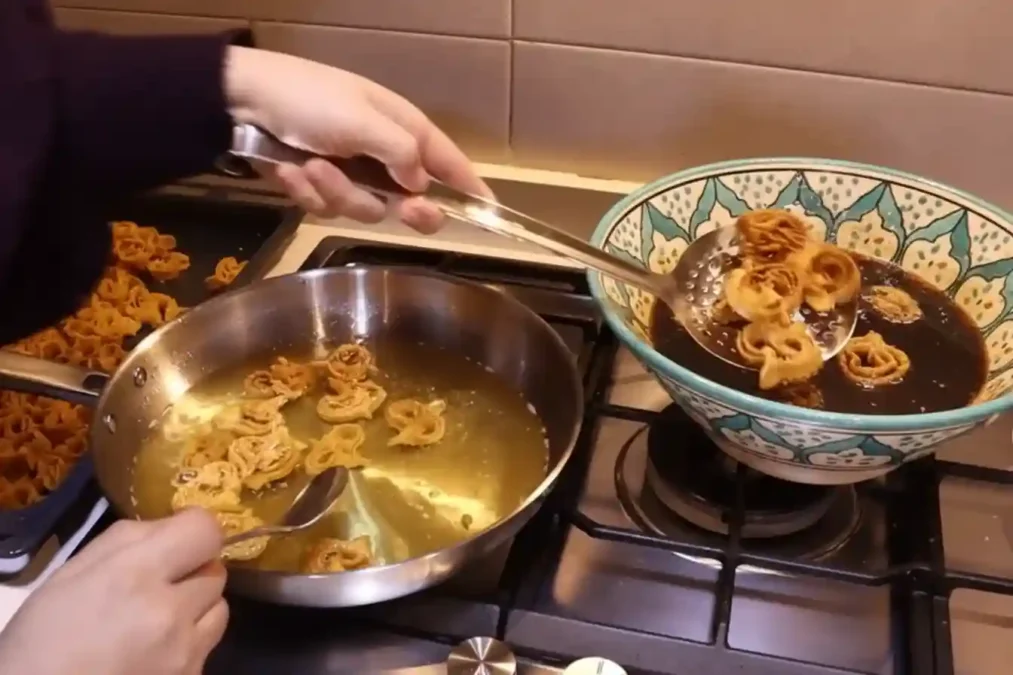 Chebakia frite trempée dans un bol de miel chaud après cuisson