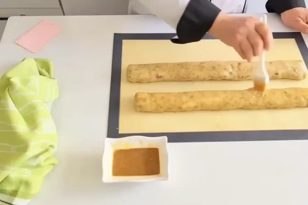 Application de dorure sur des boudins de pâte à fekkas avant la cuisson